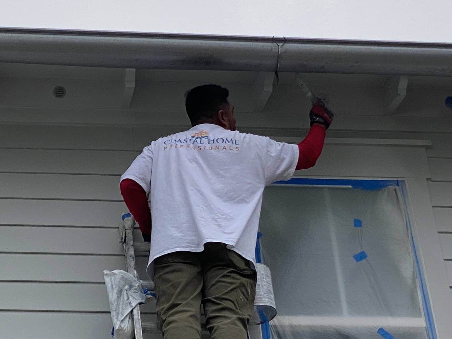 Coastal Home Professional painter is painting the eaves of the roof